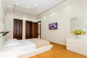 a white bedroom with a bed and a tv at Cityscape Luxury Apartment in Tbilisi City