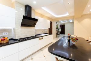 a kitchen with a black counter top and white cabinets at Cityscape Luxury Apartment in Tbilisi City