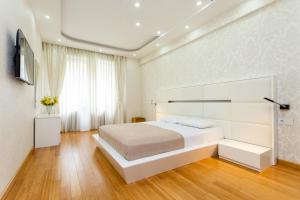 a white bedroom with a large bed and a window at Cityscape Luxury Apartment in Tbilisi City +27 photos