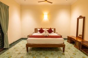 a bedroom with a bed with red pillows at Nadhima Villas in Kumbakonam