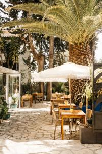 a patio with tables and chairs and palm trees at Hôtel Le Petit Castel in Antibes