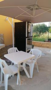 a white table and chairs under an umbrella at Villa Porto fossa in Marzamemi