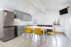 a kitchen with a white table and yellow chairs at CASA MAJOR Appartamenti in Cervia