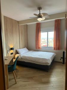 a bedroom with a bed and a desk and a window at Hotel Alain by Dynamic Hotels in Silla