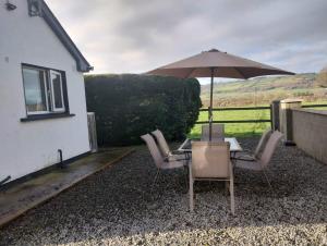 a table and chairs with an umbrella next to a house at Hillview in Royaloak