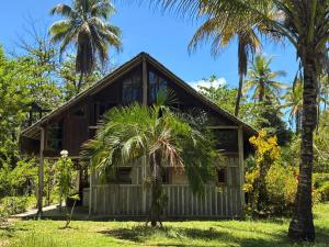a house with palm trees in front of it at Casa Tassimirim in Ilha de Boipeba