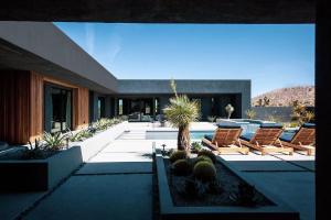 a courtyard with chairs and cacti in front of a house at Black C House Modern w pool spa in Yucca Valley