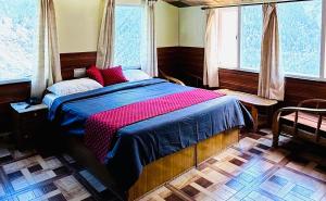 a bedroom with a bed with red pillows and two windows at Hotel Buro The Gate in Kalpa