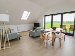 a living room with a table and chairs and a couch at Glynllifon 7 in Llanallgo