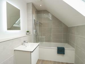 a bathroom with a white sink and a bath tub at Glynllifon 7 in Llanallgo +9 photos