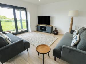 a living room with two couches and a tv at Glynllifon 5 in Llanallgo