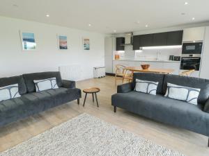 a living room with two couches and a kitchen at Glynllifon 5 in Llanallgo