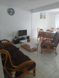 a living room with chairs and a table and a tv at Résidence EmiRose in Rivière-Pilote