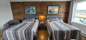 two beds in a room with wooden walls at Le Pirate Motel et Camping in Cap-Chat