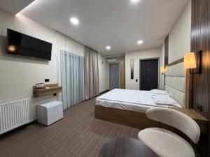 a bedroom with a bed and two chairs and a tv at Hotel DIAMOND - სასტუმრო დაიმონდ in Akhaltsikhe