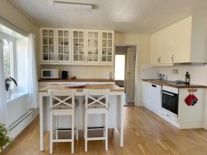 a kitchen with white cabinets and a island with bar stools at A pearl in Lofoten in Leknes