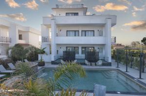 a white house with a swimming pool in front of it at Viroga Suite Apartments in Castel Volturno