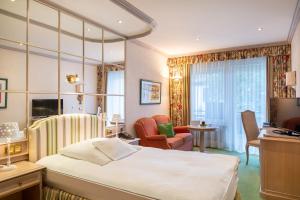 a hotel room with a bed and a desk at Relais & Châteaux Hotel Schwarzmatt in Badenweiler