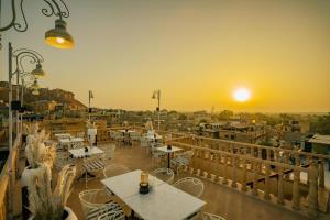a balcony with tables and chairs and the sunset at Golden Celestial haveli jaisalmer in Jaisalmer