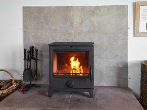 a stove in a room with a fireplace at Angerton Cottage in Carlisle