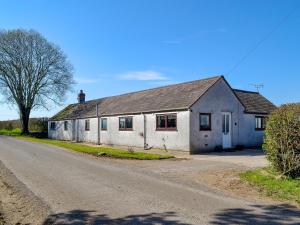 an old white building on the side of a road at Angerton Cottage in Carlisle