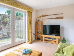 a living room with a tv and a sliding glass door at Smugglers Den in Beadnell