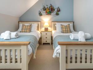 two twin beds in a bedroom with blue walls at Smugglers Den in Beadnell +10 photos