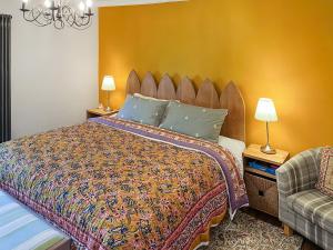 a bedroom with a large bed and a chair at Bailey Cottage in Staindrop