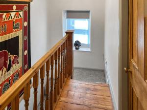 a hallway with a wooden staircase and a window at Bailey Cottage in Staindrop
