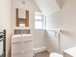a white bathroom with a sink and a mirror at Whit's End House in Whitstable