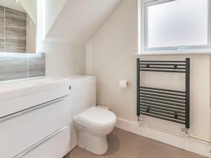 a white bathroom with a toilet and a window at Whit's End House in Whitstable