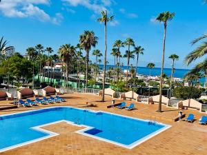 a pool with chairs and palm trees and the ocean at ACAPULCO AMAZING VIEWS. POOL. FREE WIFI in Playa Fañabe