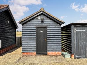 a small blue shed with a door in the middle at Fuschia Chalet in Framlingham
