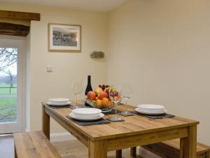 a wooden table with a bowl of fruit and wine glasses at Tarn Rigg Cottage - Uk1368 in Keswick