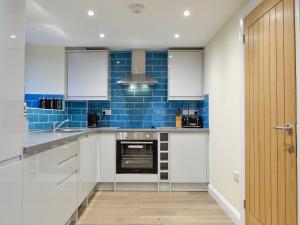 a kitchen with white cabinets and blue tiles at Tarn Rigg Cottage - Uk1368 in Keswick +14 photos