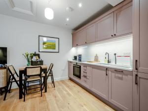 a kitchen with white cabinets and a table with chairs at The Colleys in Lechlade