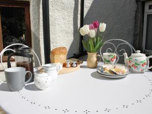 a table with cups and plates of food and flowers at Bell Hill Cottage in Lindale