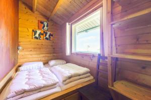 a small bed in a wooden cabin with a window at Camping Oudesluis in Oudesluis