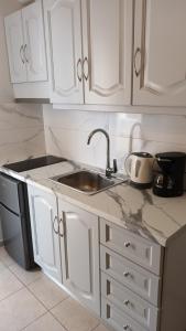 a kitchen with white cabinets and a sink at Kelenis Apartments in Karterados