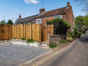 a wooden fence in front of a house at Painter's Cottage in Hemsby