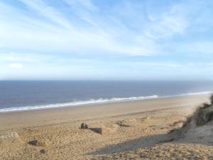 a sandcastle on a beach near the ocean at Painter's Cottage in Hemsby
