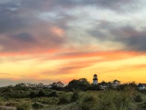 a lighthouse on a hill with a cloudy sky at Painter's Cottage in Hemsby