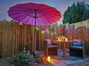 a patio with a table with a pink umbrella at Painter's Cottage in Hemsby +15 photos