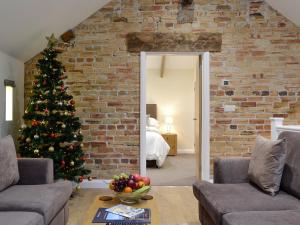 a christmas tree in a living room with a brick wall at Mary Rook Cottage - Uk1369 in Keswick
