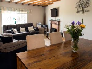 a living room with a table with a vase of flowers on it at Ash Cottage E1224 in Addlethorpe