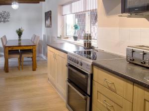 a kitchen with a stove top oven next to a table at Ash Cottage E1224 in Addlethorpe