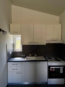 a kitchen with white cabinets and a sink at Villa Alonia House in Kallithéa