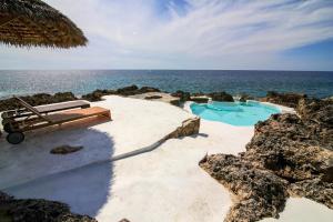 a swimming pool on the beach next to the ocean at Tingalaya's Retreat in Negril