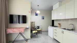 a kitchen with white cabinets and a tv on the wall at Leveta Botanical Garden in Batumi