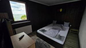a small bedroom with a bed and a window at Casa Pescărușul Vesel in Baziaş